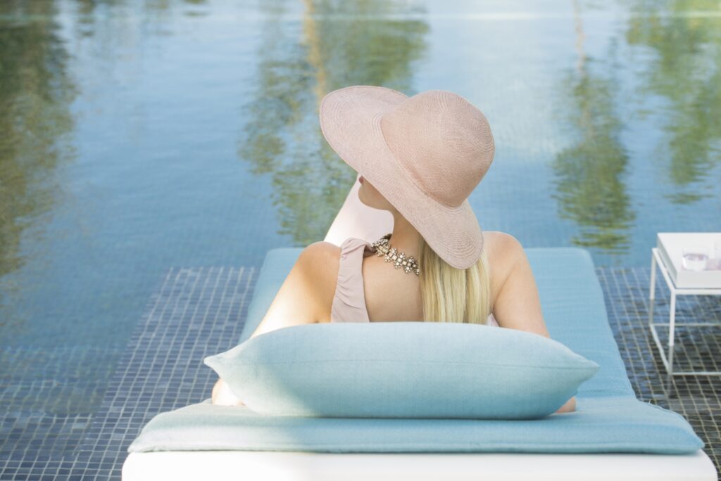 woman in glam sunhat on a sun lounger with fibreguard outdoor fabrics