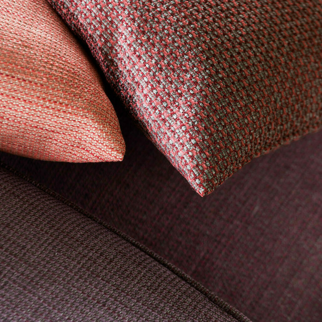closeup of two pillow details on a sofa, all with warm colours evoking a cosy feeling